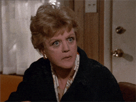 TV gif. Angela Lansbury as Jessica in Murder She Wrote shovels popcorn in her mouth as she watches something intently. 