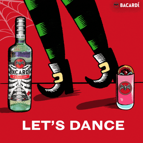 Sponsored gif. A Halloween-themed bottle of Bacardi and a cocktail in a tumbler with the Bacardi logo sit on the floor. A witch's feet are dancing between them. Text reads "LET'S DANCE."
