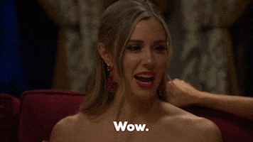 Reality TV gif. A contestant from The Bachelor looks shocked but continues smiling as she declares, "Wow."