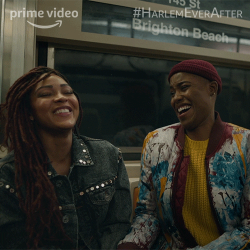 TV gif. Meagan Good as Camille and Jerrie Johnson as Tye on Harlem. They're sitting in a subway and are laughing merrily together, staring at each other and leaning in as they crack up.