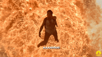 TV gif. Andy Samberg as Peralta in Brooklyn Nine Nine flails forward and falls as an explosive fire bursts out behind him.