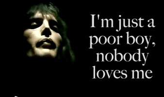 Music video gif. Freddie Mercury in the Bohemian Rhapsody music video signs “I'm just a poor boy, nobody loves me,” 