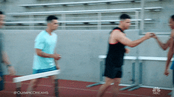 TV gif. Joe, Kevin, and Nick Jonas in Olympic Dreams with Sanya Richards-Ross and Sydney McLaughlin, Olympics athletes. They fist bump the ladies before approaching hurdles.
