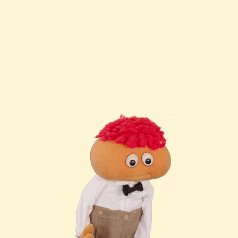 Video gif. Orange little puppet boy nervously looks around and holds his puppet hands together as he says, “Um um I just heh..heh..nevermind.”