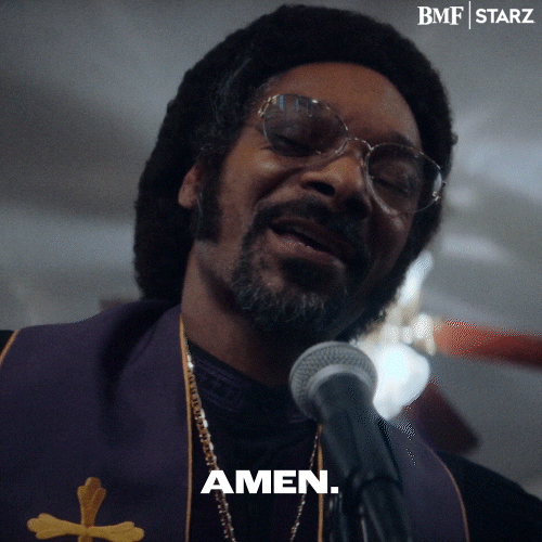 TV gif. Snoop Dogg as Paster Swift on Black Mafia Family stands in front of a mic with his eyes closed. He turns his head with a smirk on his face as he says, “Amen.” into the microphone.