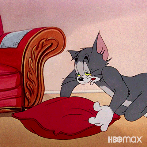 TV gif. Tom from Tom and Jerry, exhausted, fluffs a large red floor pillow before flopping down onto it face-first.
