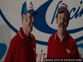 Movie gif. In a scene from Talladega Nights, Will Ferrell as Ricky Bobby and John C. Reilly as Cal smile to an offscreen crowd as camera flashes go off. Cal holds up a fist, and Ricky makes an exaggerated lever-pulling gesture before they both do a fist bump.
