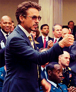 Movie gif. Robert Downey Jr. as Tony Stark in Iron Man puts his hands up to his lips to blow sarcastic kisses, and gives a thumbs up.