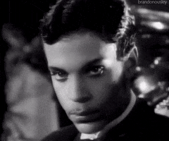 Celebrity gif. Prince is shot in black and white and he gives us his signature deadpan stare into our souls and says, "Boo."
