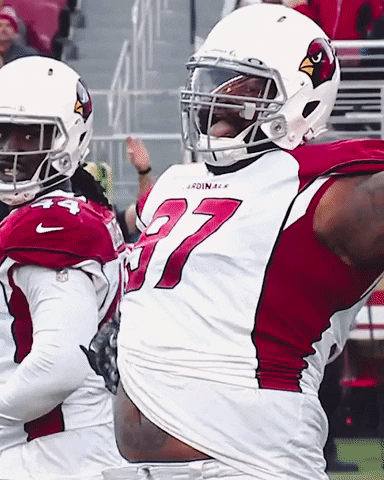 Sports gif. Jordan Phillips in his Arizona Cardinals uniform sticks his tongue out and rubs his belly.