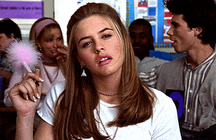 Movie gif. Alicia Silverstone as Cher Horowitz from Clueless deeply ponders at her desk while loosely holding her fuzzy pink pen. She exhales softly before returning her attention back to class.