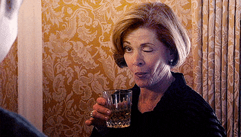 Arrested Development gif. Jessica Walter as Lucille Bluth starkly winks one eye, her lips pursed as she raises a glass of whisky.