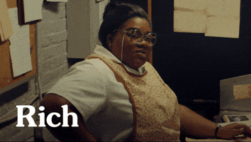TV gif. Da'Vine Joy Randolph as Rosie in "The Holdovers" sits at a desk turning to look at us as she says, "Popular combination around here. Rich and dumb'