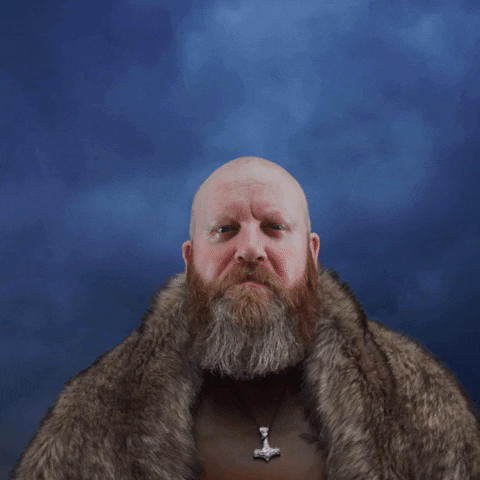 Video gif. A Norse man wearing a fur coat and necklace looks proud as he says, "My brother," lightning flashes in the background dramatically. 