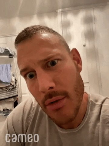 Celebrity gif. Tom Hopper is recording a selfie and his head is tilted as he stares at us. He squints and peers closer.