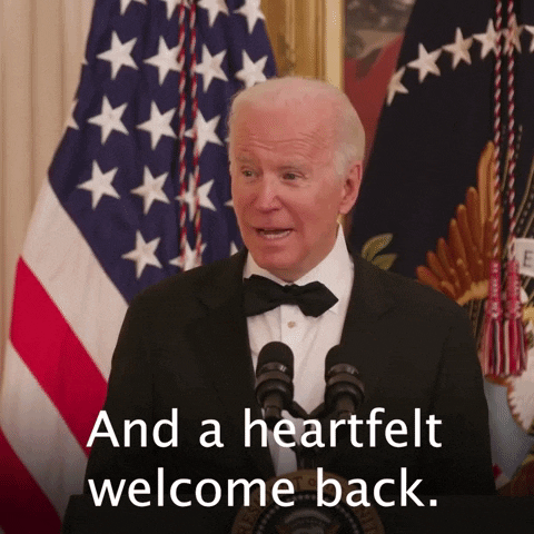 Video gif. Joe Biden stands in front of an American flag in black tie attire, addressing an audience. Text, "And a heartfelt welcome back."