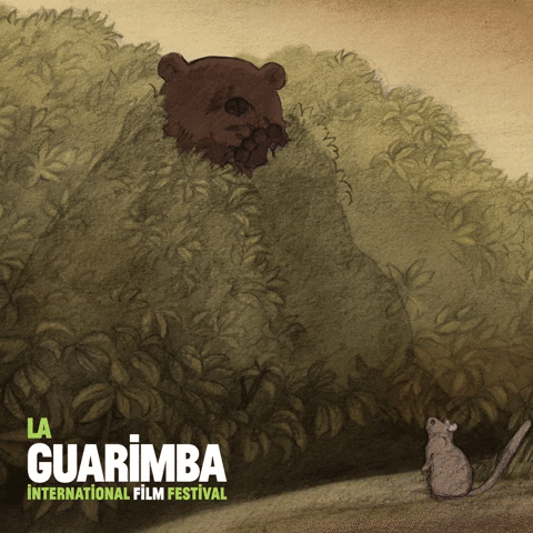 Illustrated gif. Fearsome bear hiding in a bush pokes its head out and uses its paw to brush away the leaves, roaring at a little mouse who stares up at it. We zoom in on the bear's frightening face as it roars. Text, "La Guarimba International Film Festival."