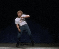 Movie gif. Jon Heder as Napoleon in Napoleon Dynamite dances a choreographed dance on stage, putting his whole body and energy into it, reaching his arms in every direction, while wearing his snow boots. 