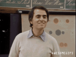 Celebrity gif. Carl Sagan bites his bottom lip while smiling and nodding his head. He then points his finger towards us and freezes. Text, “You’re awesome.”