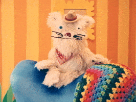 TV gif. Scruffy, a fluffy puppet dog wearing a tiny cowboy hat and bandana, in "Happy Place" sits on top of an easy chair in a bright orange cartoonish room. One eye appears to be bulging which gives him a stressed-out appearance. Text, "Looks like we made it to the end of the day!'