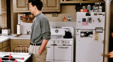 Friends gif. Matthew Perry as Chandler stands in his apartment before being tackled by Matt LeBlanc as Joey, who opens the door and hugs him from behind.