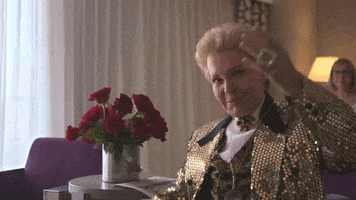 Celebrity gif. Walter Mercado, a famous Puerto Rican astrologer, crosses his arms in a flashy pose for us as he drips in his quintessential sequins and style. 