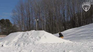 Sports gif. Snowboarder on a Salomon board launches off a jump, catching air, performing a mosquito air maneuver.