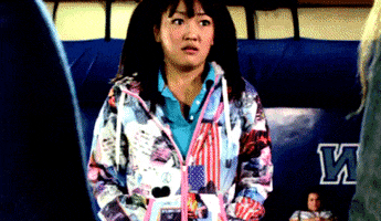 TV gif. Amy Okuda as Tinkerballa on The Guild has her hands in her jacket pockets and she looks at two people with a confused expression.