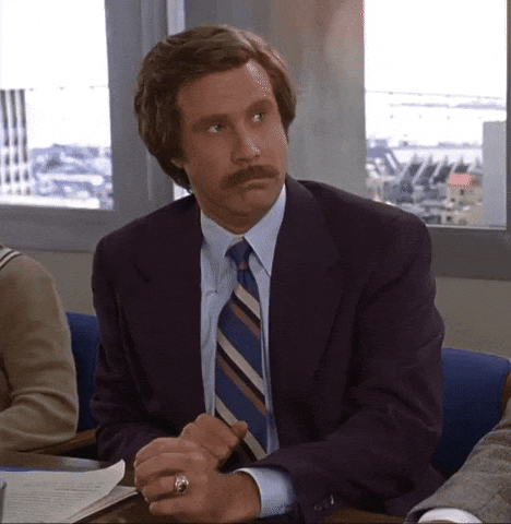 Movie gif. Will Ferrell as Ron in Anchorman tilts his head and raises a hand in indifference. 