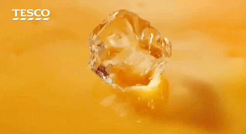 Tesco orange juice with an ice drop causing a splash in slow motion