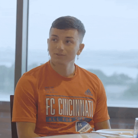 Sports gif. Clip of soccer player Alvaro Barreal seated at a table with his hands clasped together as he reacts with an "Ooh," like he's impressed or embarrassed at something someone just said. 