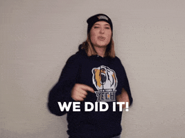 Video gif. Woman wearing a New York Institute of Technology sweatshirt and hat pumps her fist and points at us in a celebratory manner. Text, "We did it!"