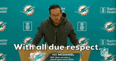 Video gif. Mike McDaniel, head coach of the Miami Dolphins, raises his arms like he's trying to calm everyone down saying, "With all due respect."  