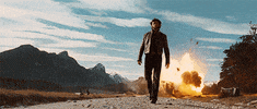 Movie gif. Hugh Jackman as Wolverine in X-Men Origins walks toward us down a gravel road while a scene behind him bursts in a huge explosion.