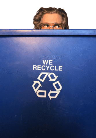 Video gif. A man peeks out from behind a blue recycling bin. We can only see half his face and he's scanning up and all around in a shifty or nervous way.