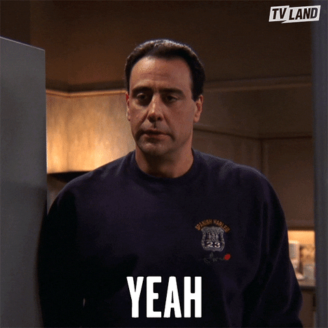TV gif. Wearing a dark sweatshirt with police insignia, Brad Garrett as Robert Barone from Everybody Loves Raymond gives us a timid nod. Text, "Yeah."