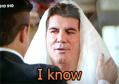 Reality TV gif. A groom in the foreground holds the veil of his "bride", an annoyed Simon Cowell on American Idol. Simon looks to left of frame and says: Text, "I know."
