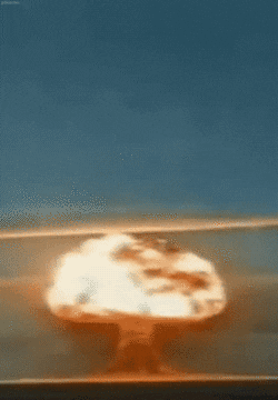 Video gif. An explosion rises from the ground with flames erupting into a cloud of smoke.