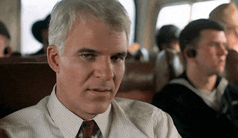 Movie gif. Riding on a bus, Steve Martin shakes his head and sighs, but still looks fairly upbeat.