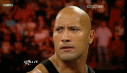 Sports gif. Dwayne The Rock Johnson is in the WWE ring. His bald head glistening, he breaks into a wide and mischievous smile. He's about to throw down in the best way.