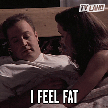 TV gif. Actors Leah Remini and Kevin James of King of Queens cuddle in bed. Kevin says "I feel fat." and pulls away from his TV wife.