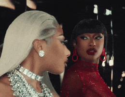 Music video gif. Megan Thee Stallion in her video for Big Ole Freak. She's wearing a sparkly red ensemble and red lipstick as she sticks her tongue out a mirror image of herself wearing an all diamond ensemble.