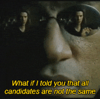 Movie gif. Close-up of Laurence Fishburne as Morpheus wearing sunglasses that reflect an image of a stunned Keanu Reeves as Neo. Morpheus says, “What if I told you that not all candidates are the same?” He then reveals a red pill and a blue pill in his open hands.