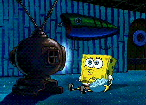 A yellow square cartoon figure, holding a bowl of popcorn watching tv in his home underwater. 
