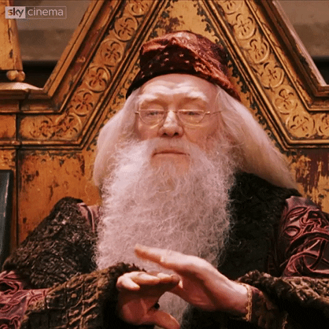 Movie gif. Richard Harris as Dumbledore from Harry Potter looks down at the hall of children with an almost bored expression on his face. He holds one hand out and pats it with his other hand as a way of clapping politely.