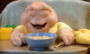 TV gif. Sitting in his highchair with a bowl of oatmeal, Baby Sinclair from Dinosaurs enjoys a hearty laugh.