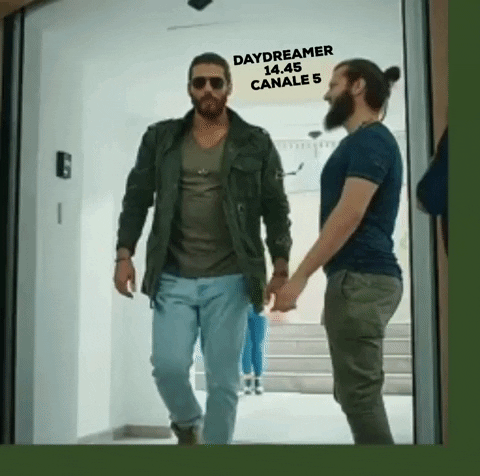 TV gif. Demet Ozdemir on Daydreamer walks through a door with a swagger in his walk. People stare at him as he walks through the door and he waves his hands up in the air. He has a cool expression on his face that’s hidden behind his dark sunglasses. Text, “Daydreamer. 14.45 Canale 5.”