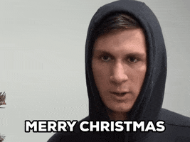 Video gif. A man with his hood up looks at us and says very seriously, "Merry Christmas." as the camera zooms in.