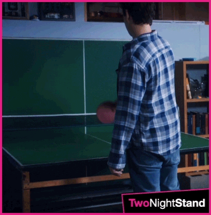 Movie gif. Miles Teller as Alec in Two Night Stand languidly paddles a ping-pong ball against the folded table, playing by himself.