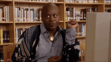TV gif. Sitting at a computer in a library, Tituss Burgess in Unbreakable Kimmy Schmidt bats his eyes then looks away in boredom.